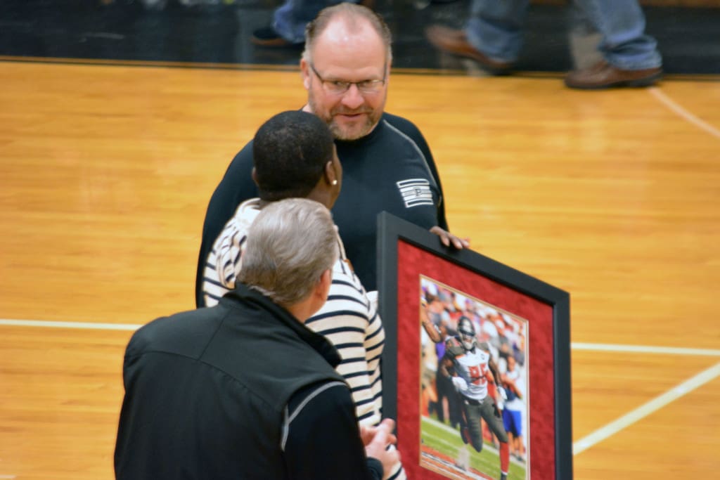 Coach Matt Kregel presents a picture to T. J. Fatinkium, PHS alum and now an NFL player.