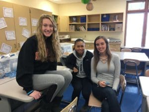 Three students sitting on a desk